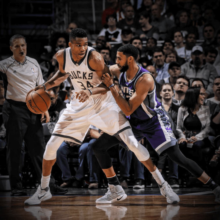Dos jugadores de la NBA de diferentes equipos luchan por el balón en la cancha.