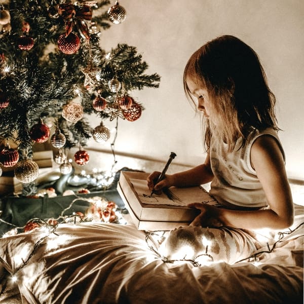 Niña escribiendo carta a Santa Claus árbol de Navidad 