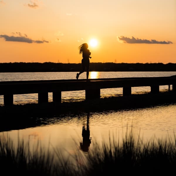 Mujer corriendo ejercicio atardecer muelle 