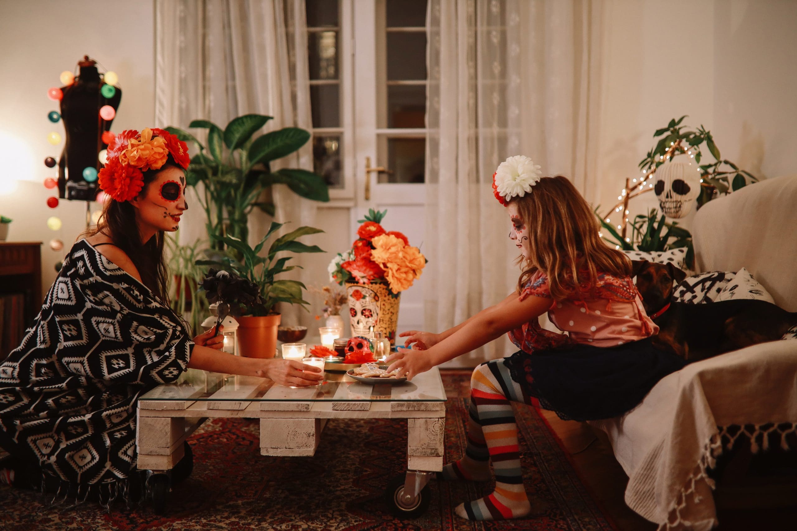 Mamá e hija en Día de Muertos con decoración y galletas de temporada. 